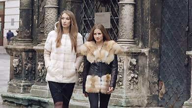 Two assured models walking runway in furry coats on the street. Slowly