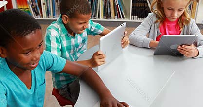 Group of school kids using digital tablet and laptop in library