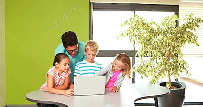 Teacher and kids using laptop in classroom