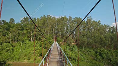 Camera Moves along Suspension Bridge over River in Park