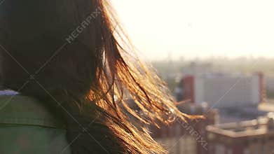 Back view. Wind blows long dark hair beautiful young women. girl standing on the roof at sunset. Slow mo
