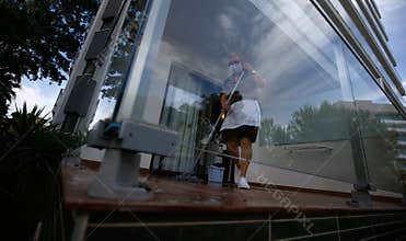 A cleaning worker wearing protective mask scrub the floor of a hotel balcony room wide