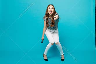 Fashionable girl in sunglasses seductive posing against blue background.