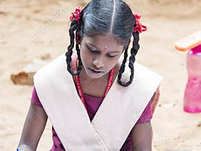 Girl classmates concentrated studying with book sitting on floor outdoor at the school playground