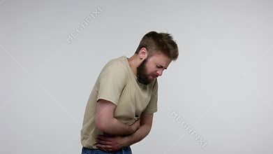 Bearded man feeling painful cramp in stomach, clasping bloated belly and suffering severe abdominal pain