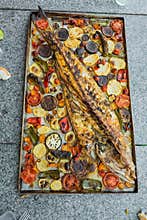 Fish baked with roasted tomatoes, potatoes and vegetables