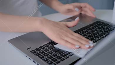 Close up: woman hands cleaning laptop keyboard with wet wipe - slow motion