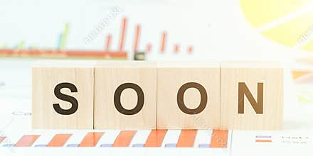 Word soon with black letters on wooden block on table