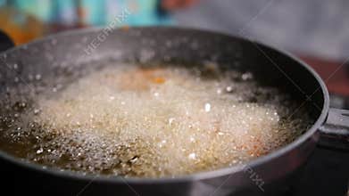 Slow motion closeup of cooking oil boiling in a shallow pan