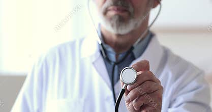 Smiling older mature male cardiologist doctor showing stethoscope to camera.