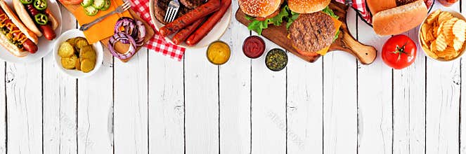 Summer BBQ food with hot dog and hamburger buffet, top border over a white wood banner background