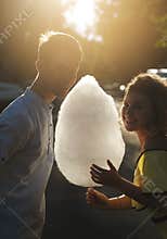 Smiling couple with cotton candy walking outdoors