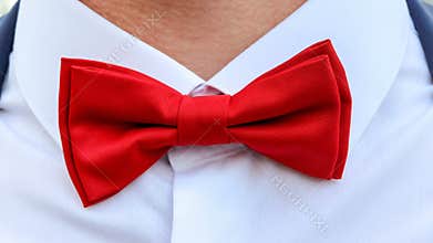Red bow tie on white shirt around man`s neck, close-up. Elegant accessory for men