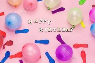 wooden letters forming happy birthday and colorful ballons on pink background , holiday concept.