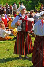 Celebrating anniversary in Turaida, Latvia with young girls playing musical instrument and performance in traditional costumes