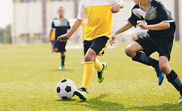 Child kicking soccer ball in a duel. Running footballers compete for the ball
