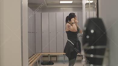 Sportive adult Caucasian woman greeting friend in gym locker room. Side view of positive beautiful sportswomen giving