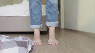 Woman taking off her clothe sin order to go to bed, bare feet close up, clothes falling down to the floor