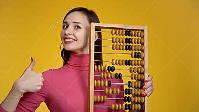 Young attractive girl holds wooden abacus in her hands.