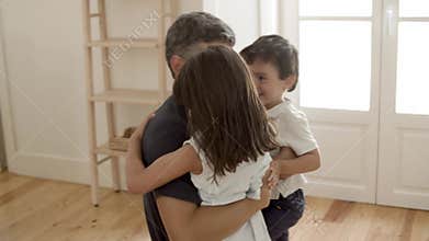 Little boy and girl running to happy dad and hugging him