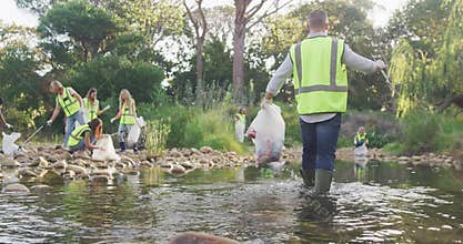 Mid adults with yellow vest volunteering during river clean-up day