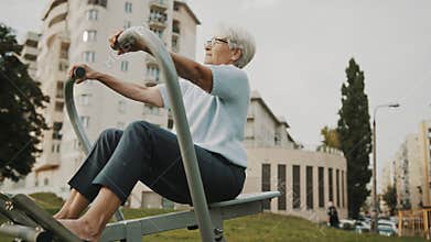 Old woman exercising in and outdoor gym. Slow motion