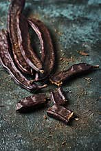 Ripe carob beans on a green surface