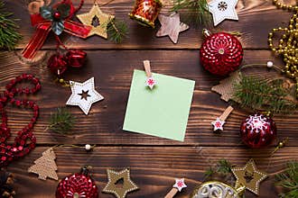 Christmas flat lay of red balloons and wooden stars and clothespins on a dark background with a square sheet for notes in the cent