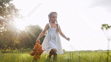 Little girl kid walk with a teddy bear toy in the park in nature. childhood dream concept. smiling kid child walk with