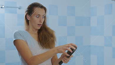 Woman looking at mirror, brushing hair. Irritated young girl dissatisfied with damaged dry hair condition, hair loss.