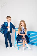 Boy and girl schoolchildren in fashionable school clothes with a school bag