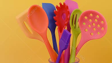 Bright multi colored kitchen utensils on yellow background