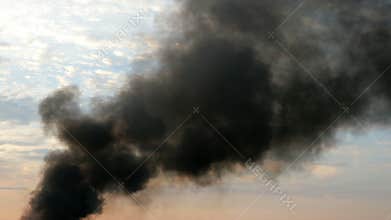 Column of black smoke in sky. This is fire, burns agricultural debris, factory pipe or explosion.