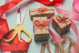 Process of packaging gift boxes. Thanks gifts. Wedding presents. Pink ribbon and yellow scissors. Red carton hearts.