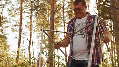 Adult man constructing picnic table in autumn forest. Father building table for family picnic in countryside forest