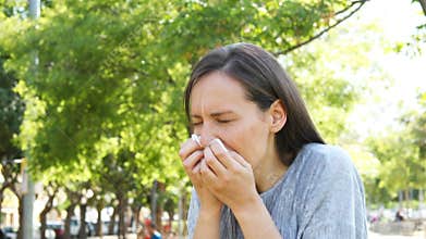 Adult woman coughing in a park
