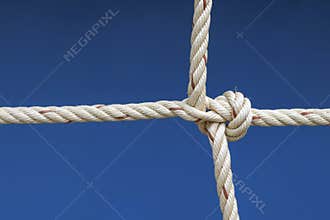 Nylon rope tied into a knot with blue background.