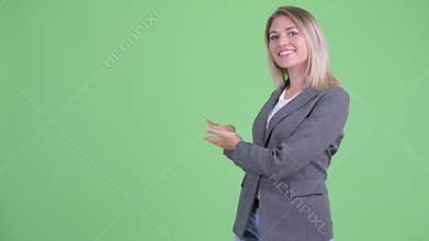 Happy young beautiful blonde businesswoman showing to the back