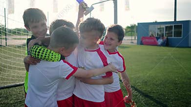 Young smiling schoolboys hold trophies and hug