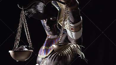 Egyptian god Anubis is holding the golden scale with a heart and fern leaf