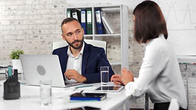 Confident businessman talking with female employee discussing business looking at screen of laptop