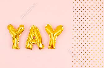 Inflated letters yay ove the pastel background with golden polka dots. Party, celebration, holidays