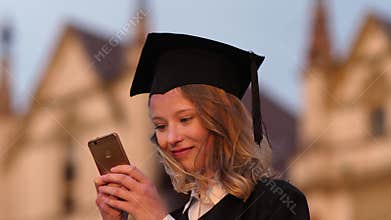 Young cute student graduate texting message on her phone.