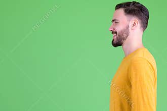 Profile view of happy young handsome bearded man smiling