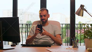 CEO of start up company typing on computer and looking at the phone in warm sunset light