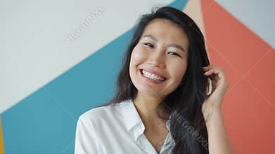 Attractive Asian female adult smiling laughing at home on colorful background