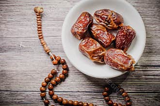 Tasbih rosary beads and Tamar Dates  against wooden background