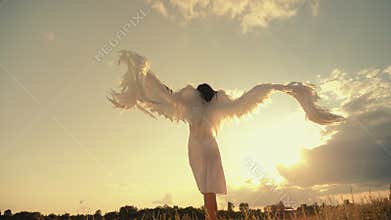 Woman in a white dress raises angel wings up
