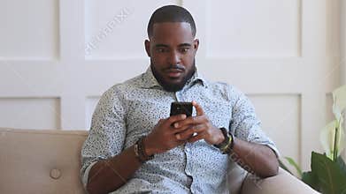 Surprised young african american man looking at mobile phone screen.