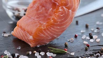 Raw salmon fillet with spices falling on a stone plate